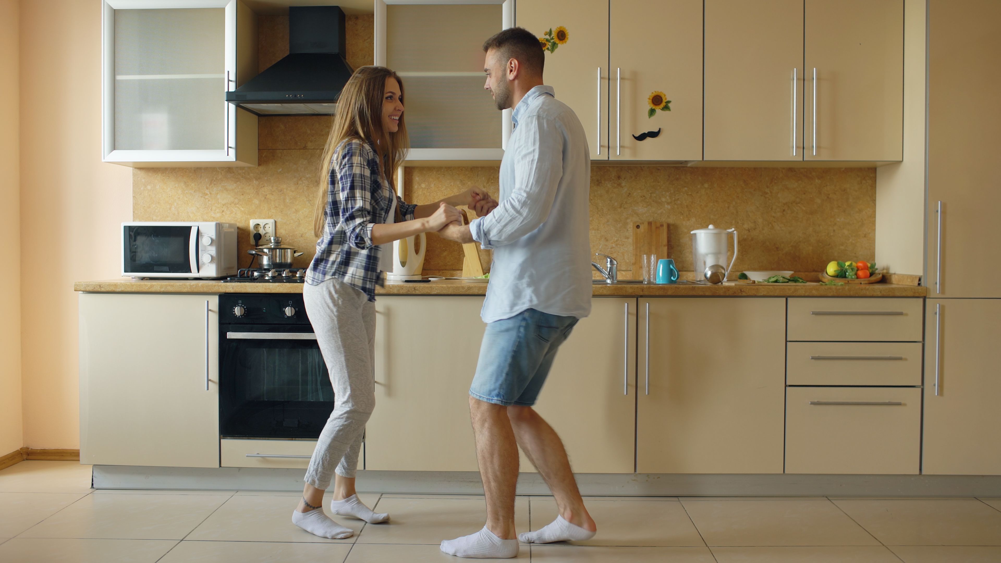 A couple joyfully dances in the kitchen, keeping everyday life playful
