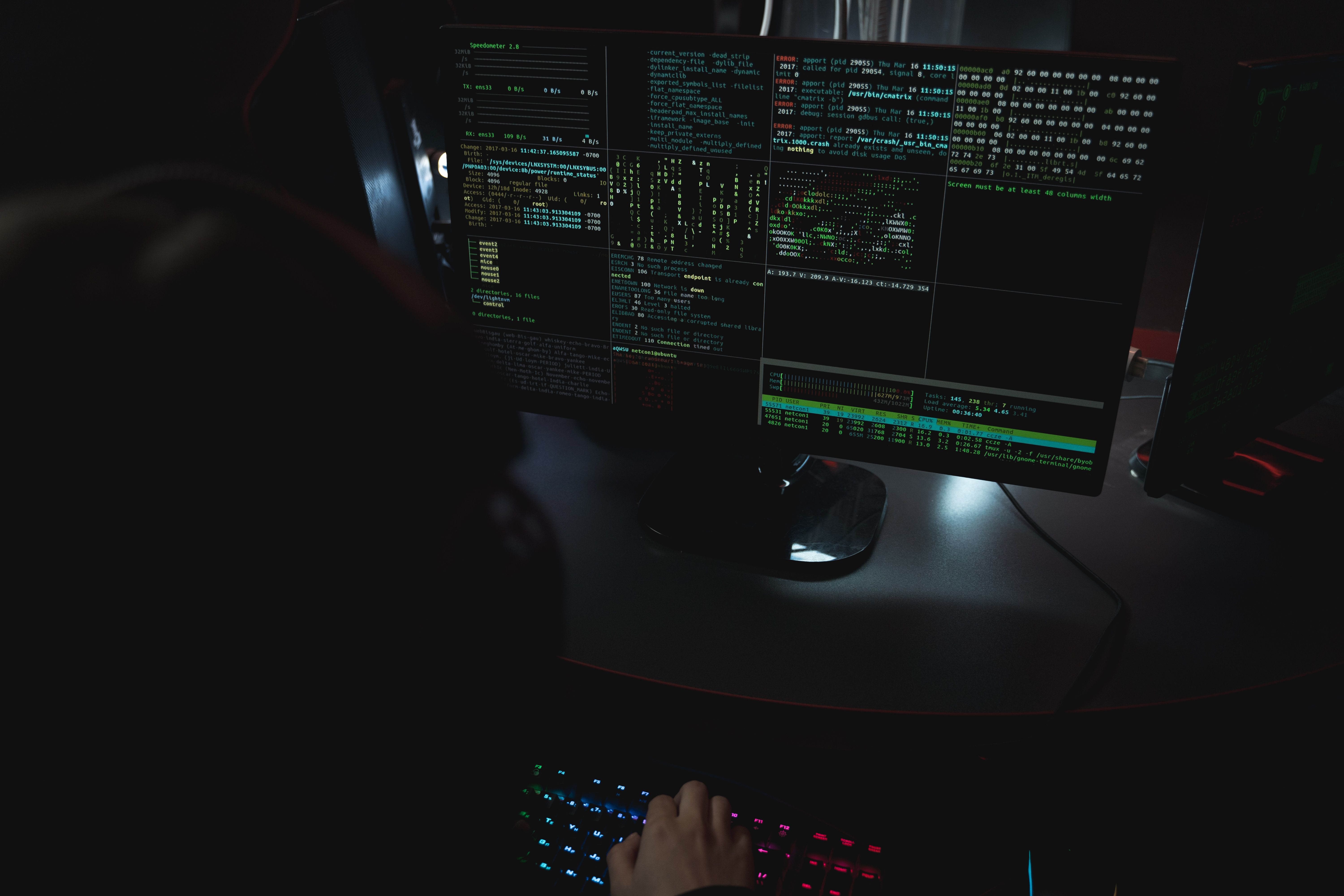 Computer monitors displaying code in a dark cybersecurity workspace