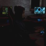 Security analyst reviewing data across multiple monitors in a dark operations room