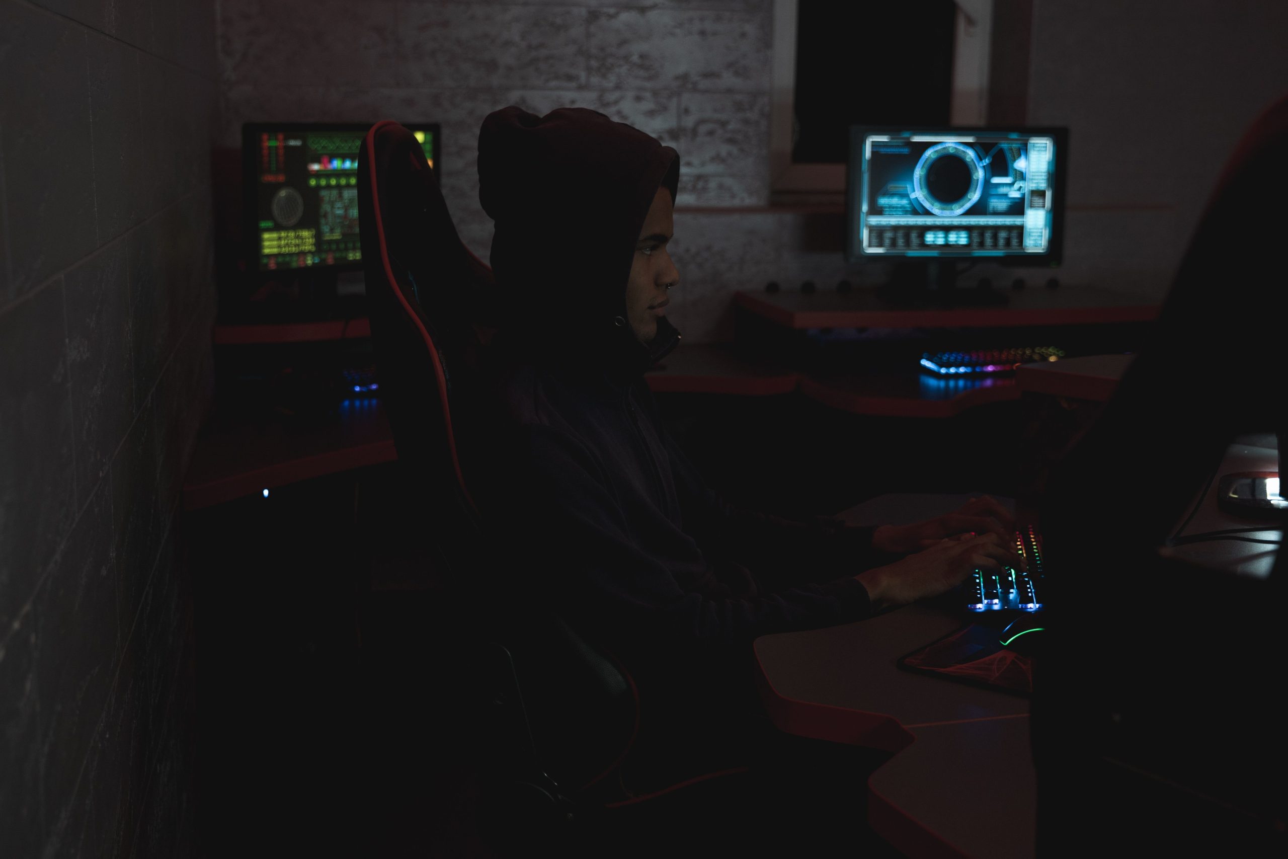 Security analyst reviewing data across multiple monitors in a dark operations room