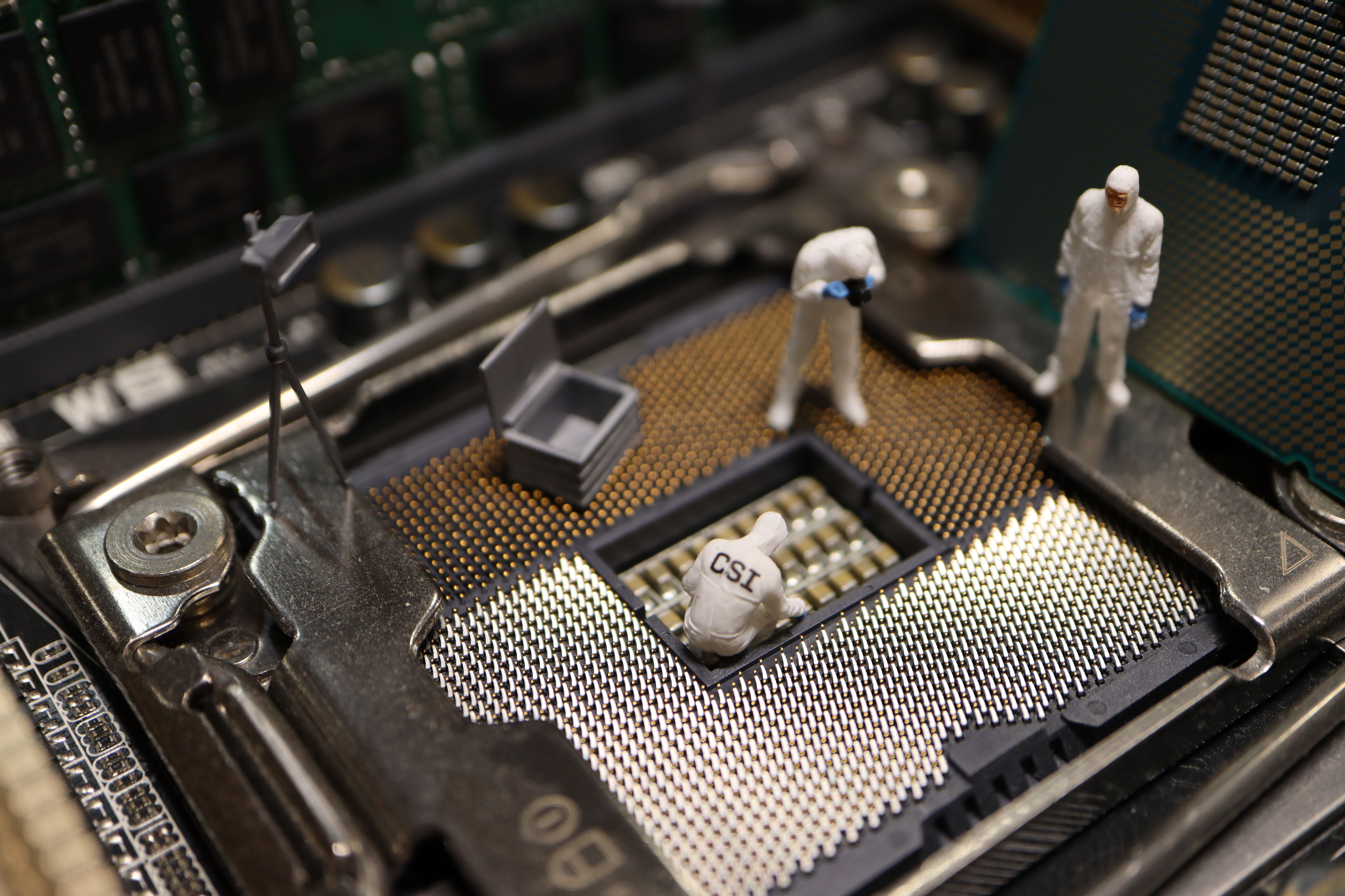 Miniature investigators examining a computer processor to represent digital forensics