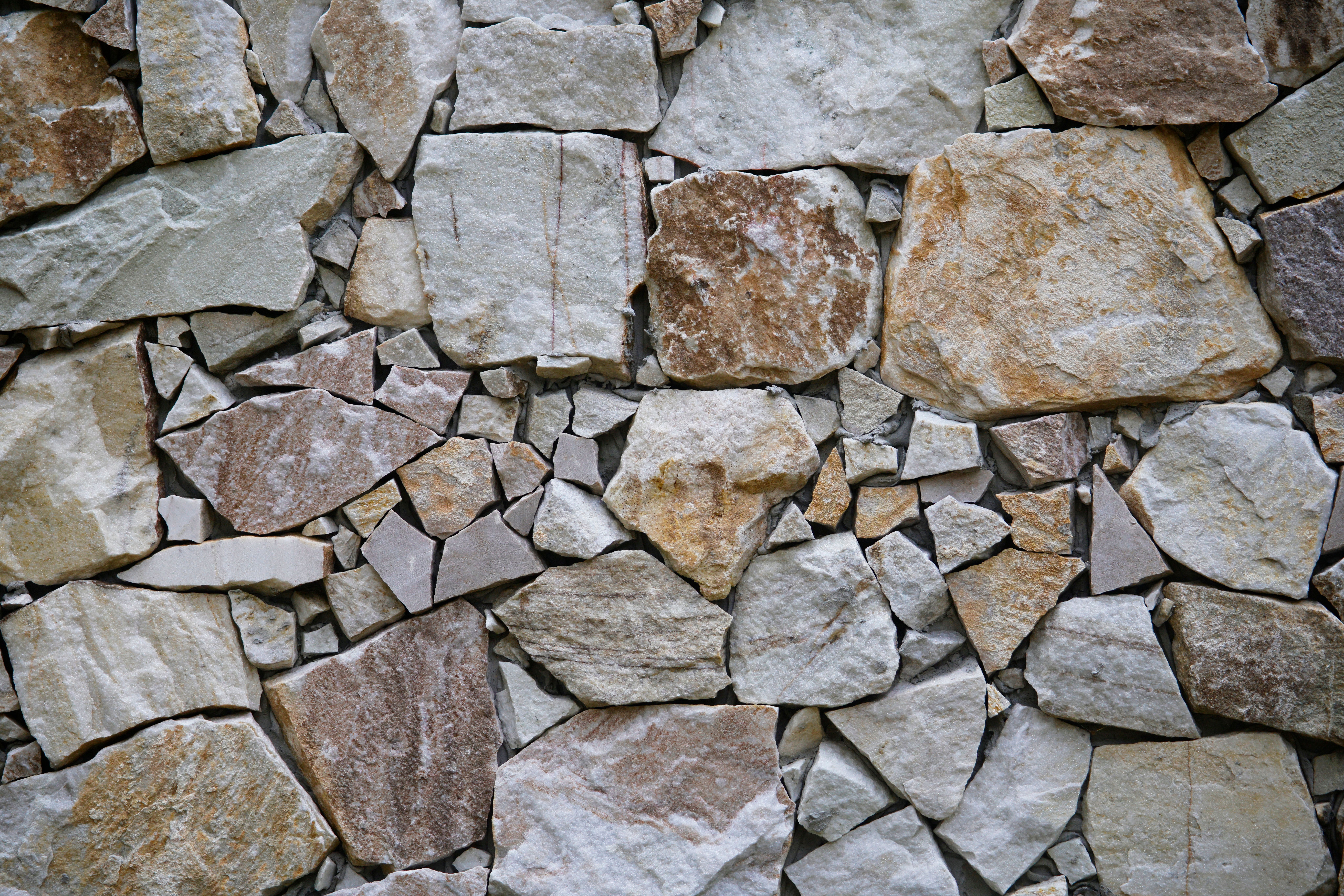 Natural stone wall built from irregular beige and gray rocks for a durable outdoor landscape feature.
