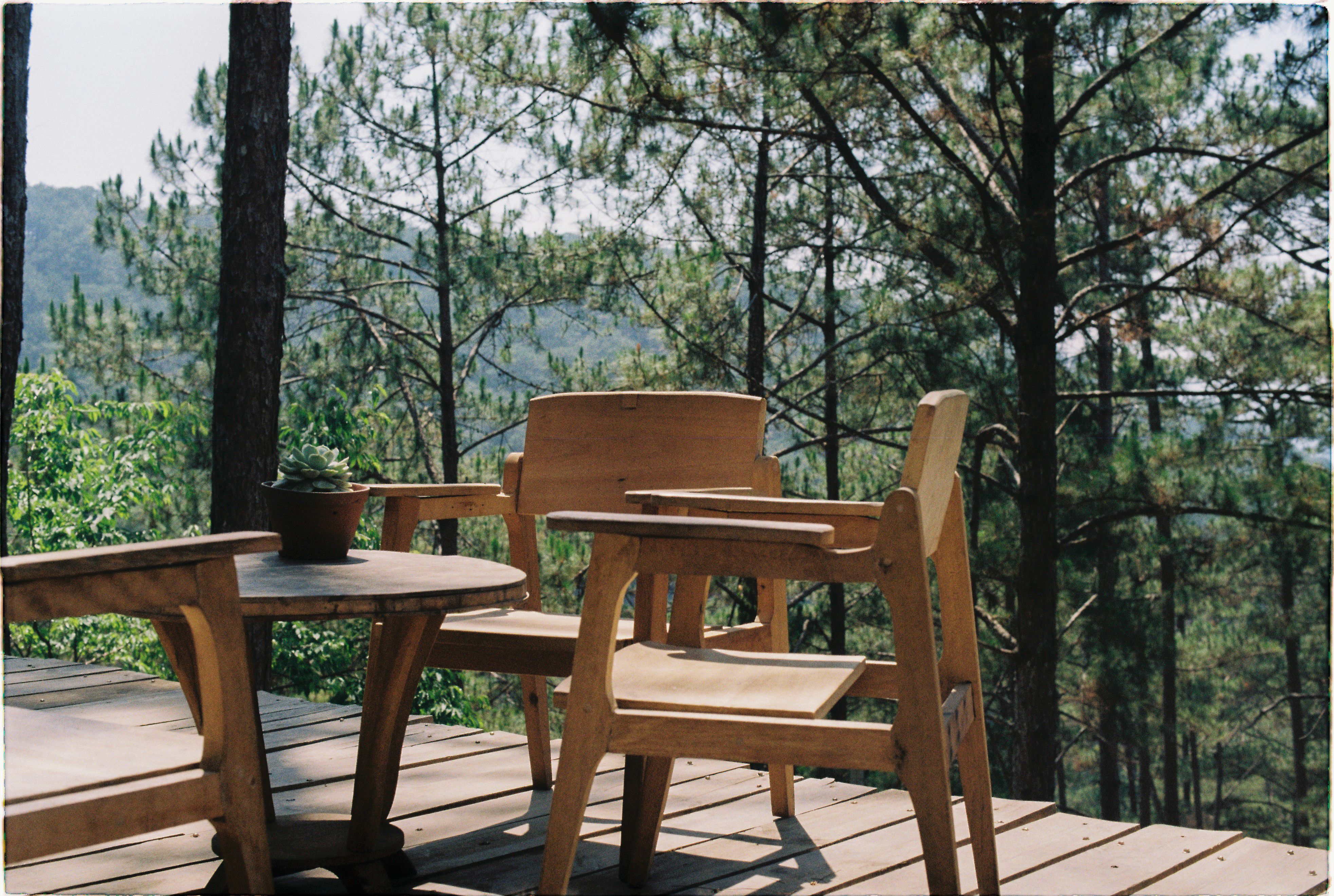 Wooden patio furniture overlooking a forest, showing a finished outdoor space built with natural materials.